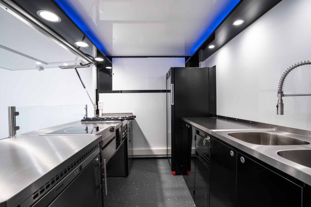 Innenansicht des Foodtruck-Ausbaus im Kia PV5 mit Edelstahl-Arbeitsflächen und Küchengeräten.